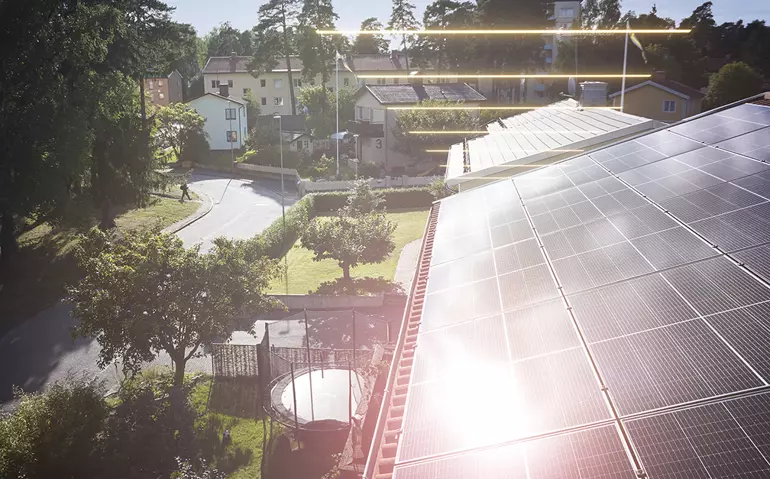 Ett hustak med solceller mitt i ett grönt bostadsområde 