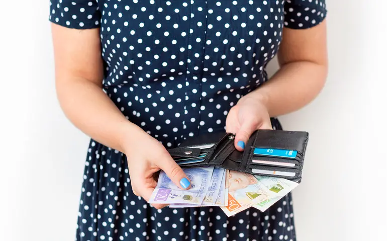 En kvinna håller i en plånbok där det sticker ut pengar
