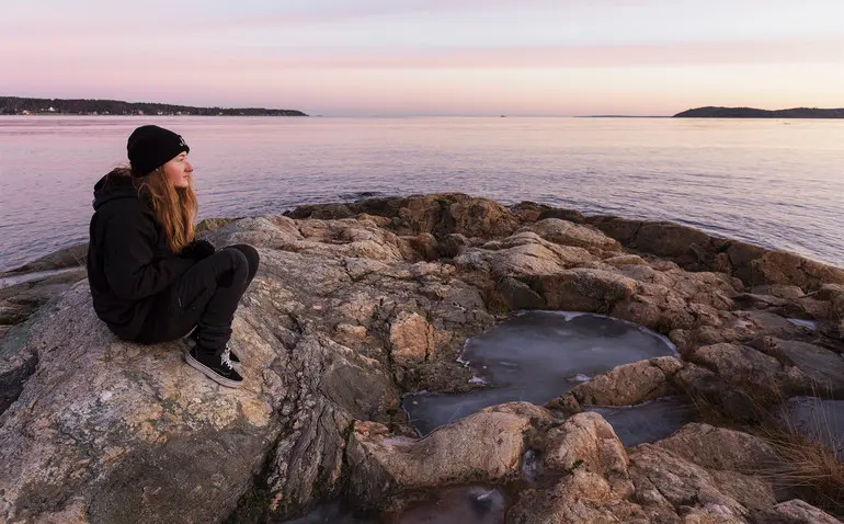 Bild på en tjej som sitter och tittar ut över havet
