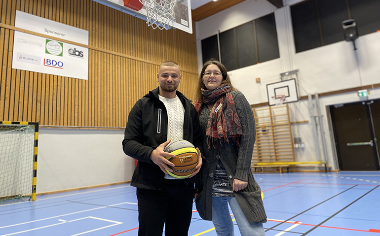 Två personer står och håller i en basketboll