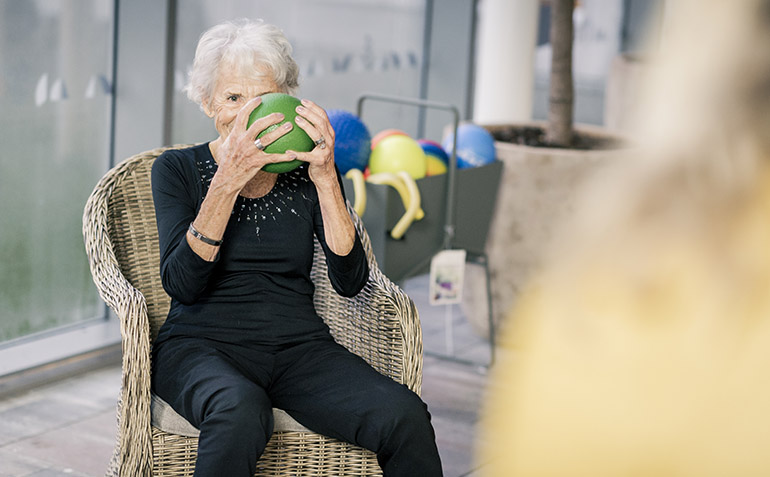 En äldre kvinna som kastar en grön boll.
