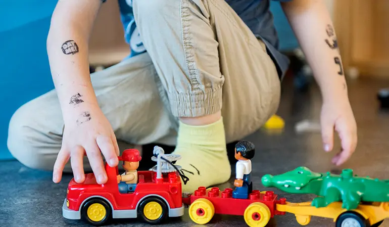 Barn leker med en färgglad leksaksbil.