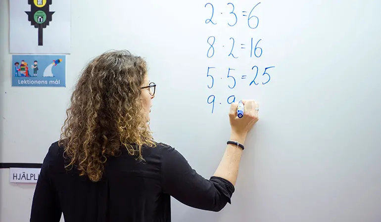 Lärare skriver upp tal på en whiteboardtavla