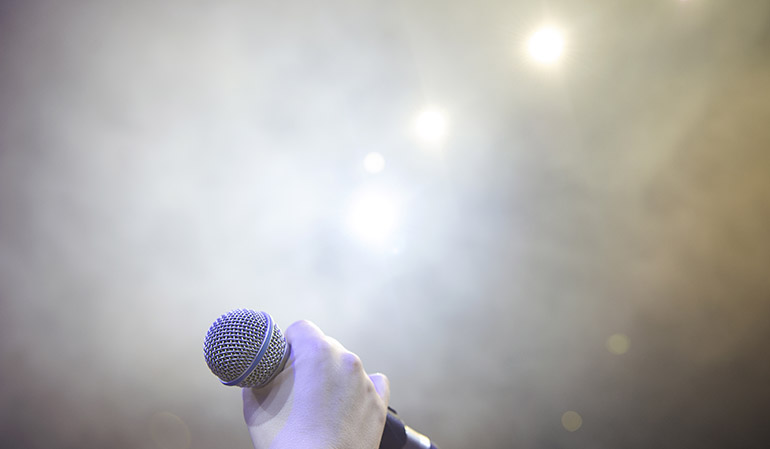 Hand håller en mikrofon på scen.