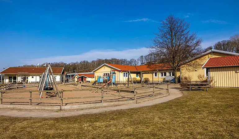 Forsgläntans förskolas byggnad och gård. Byggnaden är gul och på gården finns det klätterställningar och gungor.