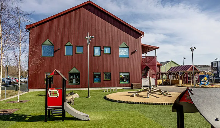 Förskolegården  med konstgräs och uteleksaker för mindre barn.