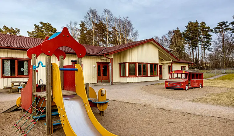 Gården på Vallda Sandö förskola. På gården finns en gul och röd rutschkana.