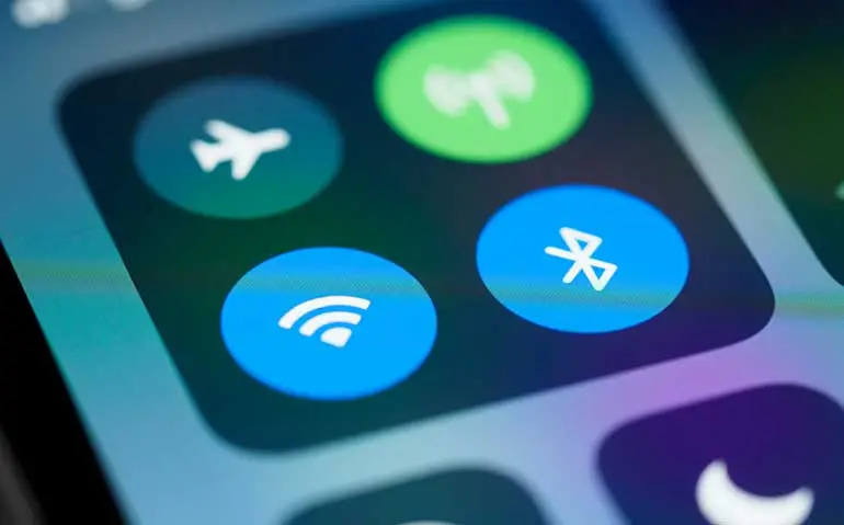 Närbild på iPhoneskärm symbolerna för wifi och bluetooth är markerade