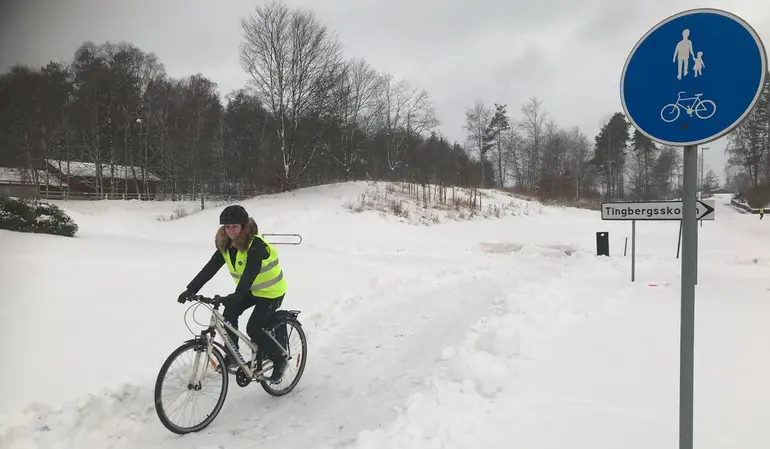 En gång- och cykelväg i ett snölandskap. På vägen finns en cyklist med hjälm och reflexväst.